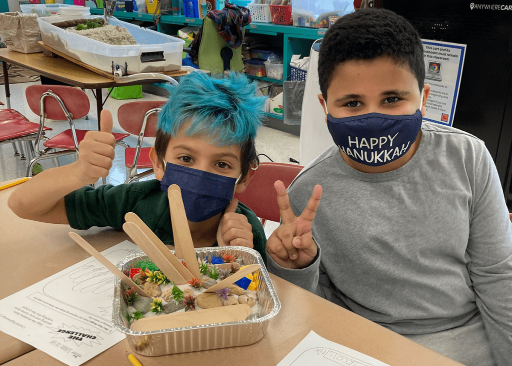 Two boys sit at a classroom table working together on an erosion engineering project.