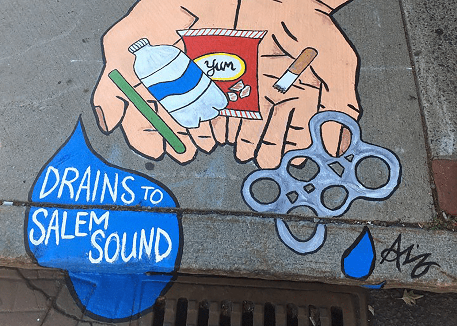 Storm drain mural painted on a sidewalk next to a storm drain in Salem, Massachusetts.